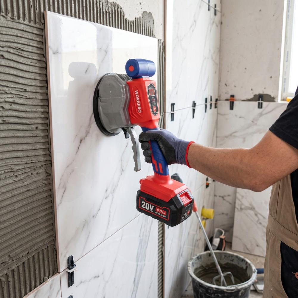 Bir işçi, duvara büyük bir mermer karo yerleştirmek için elektrikli vantuzlu alet kullanıyor.