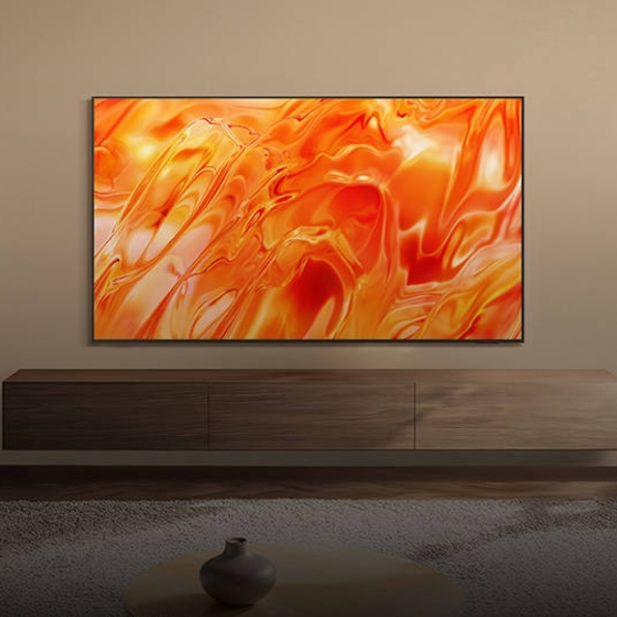 Un televisor con un fondo abstracto naranja sobre una consola de madera encima de una alfombra con un jarrón en primer plano.
