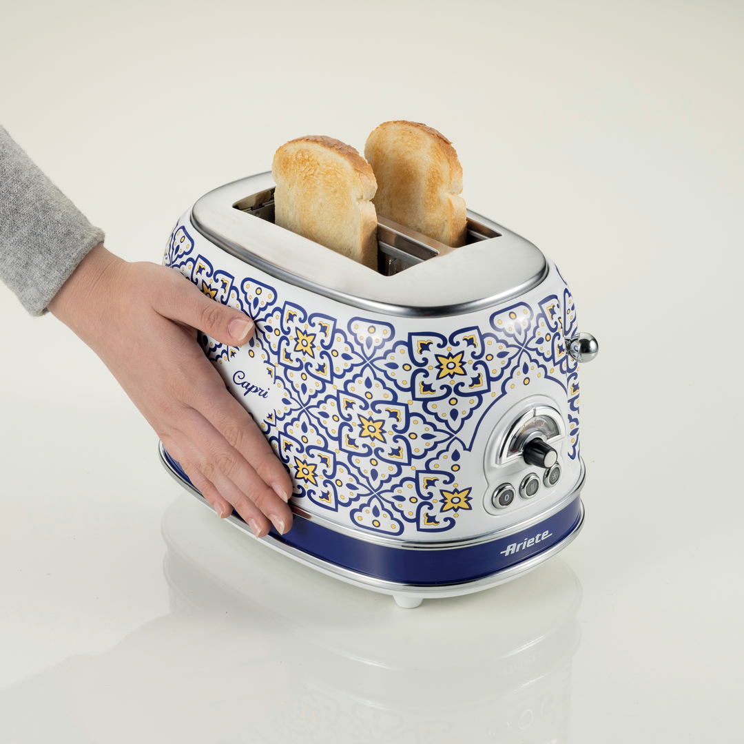 Eine Hand berührt einen weiß-blauen Toaster mit blauem Muster und zwei Toastscheiben.