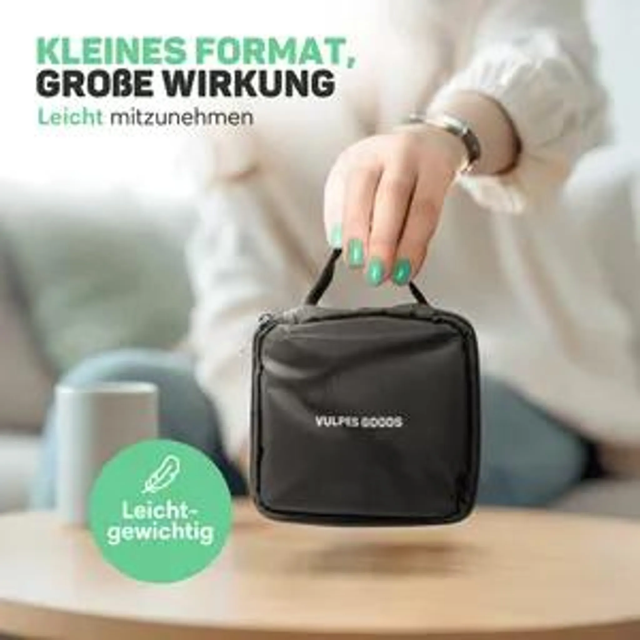 Eine Person hält eine kleine schwarze Vulpes Goods Tasche über einem Tisch.
