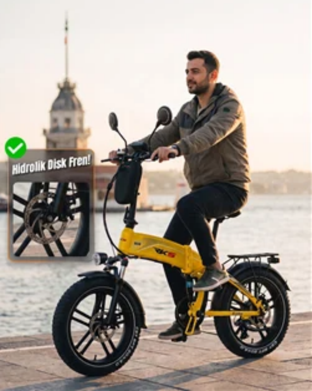 Bir adam su kenarında sarı elektrikli bisiklet sürüyor, arka planda tarihi bir kule ve deniz var.