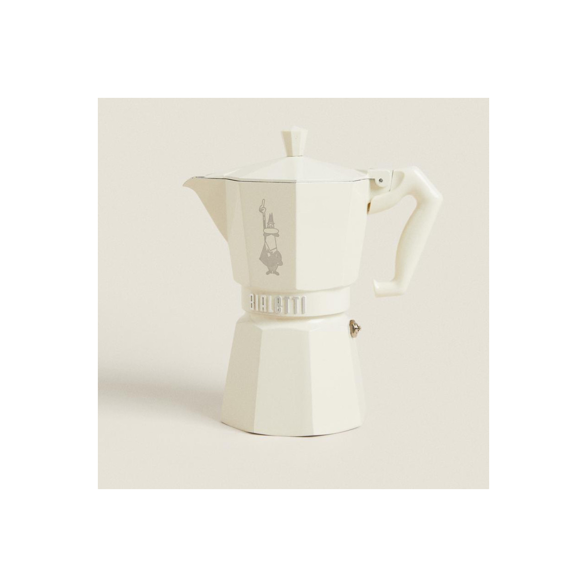 Una moka Bialetti color crema si trova su uno sfondo chiaro con un'ombra.
