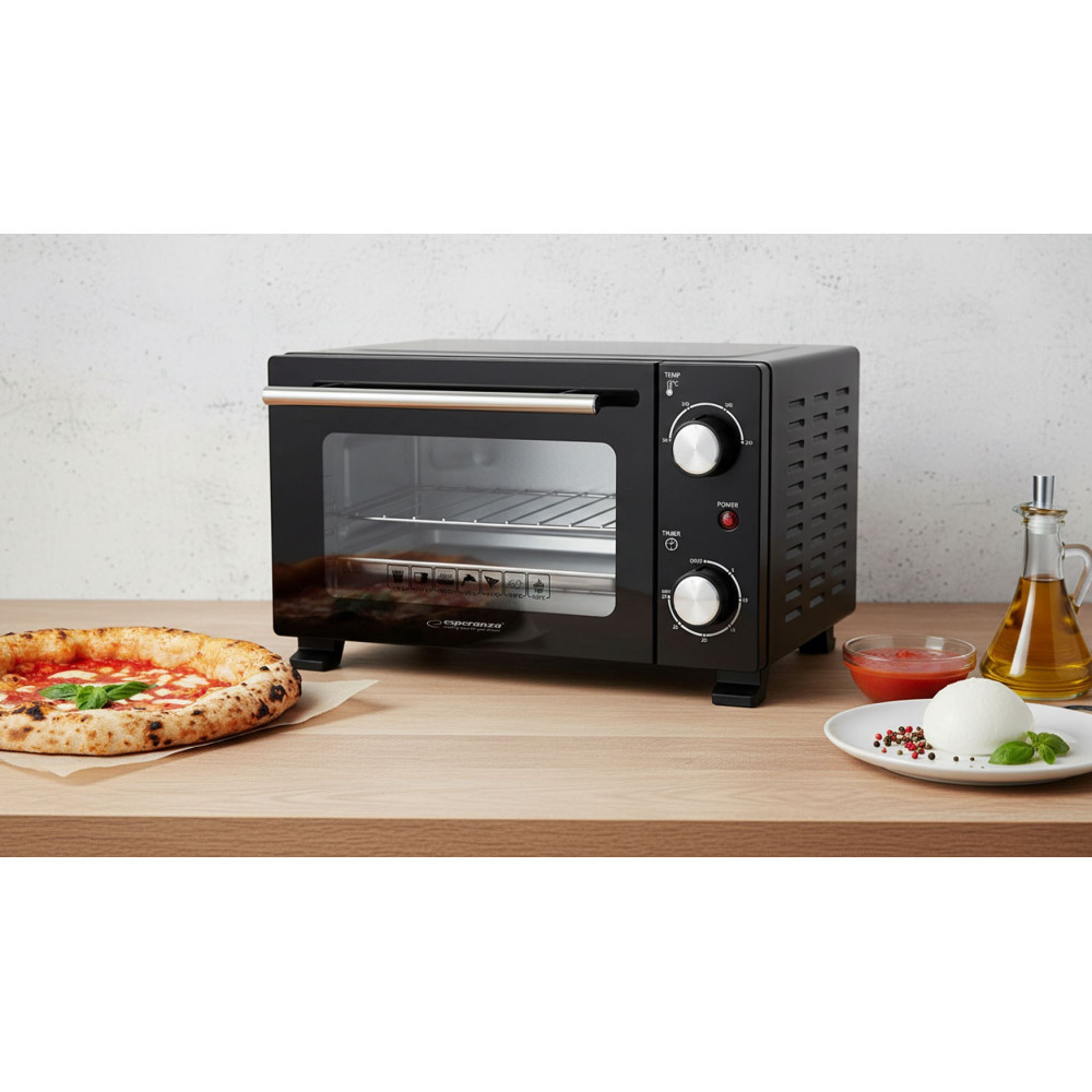 Czarny mini piekarnik na drewnianym stole, obok pizza, mozzarella, oliwa z oliwek i sos pomidorowy.