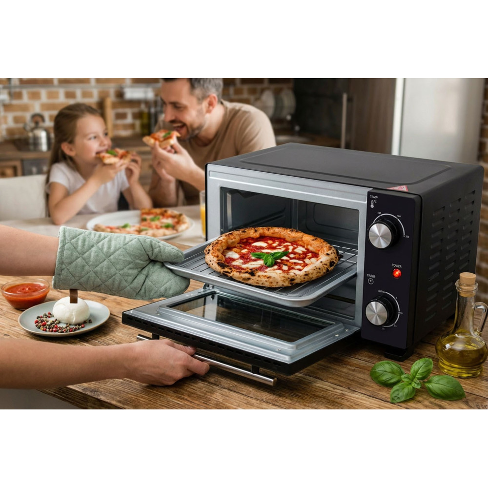 Ręka w rękawicy kuchennej wsuwa pizzę do małego piekarnika nablatowego, w tle je ojciec z córką.
