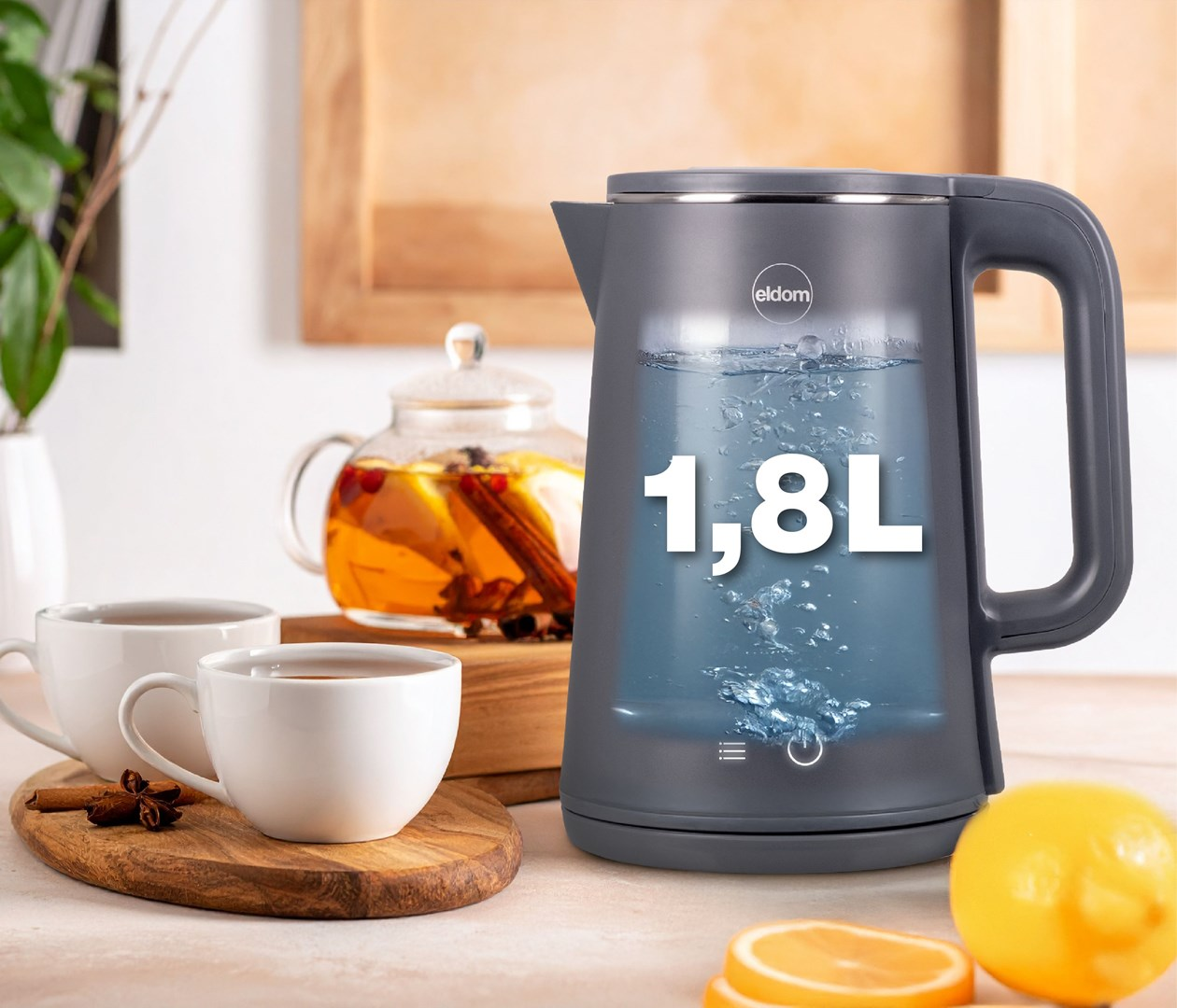 Szary czajnik elektryczny o pojemności 1,8 l, filiżanki, dzbanek i cytryny.