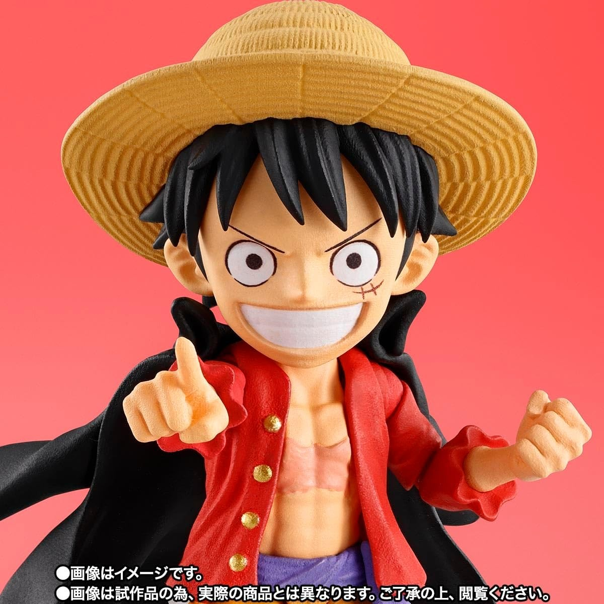 Figura de acción de Luffy con sombrero de paja, camisa roja y capa negra sobre fondo rojo.