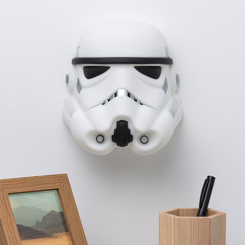 Un casco de Stormtrooper blanco montado en la pared, junto a un marco de madera y un portalápices.