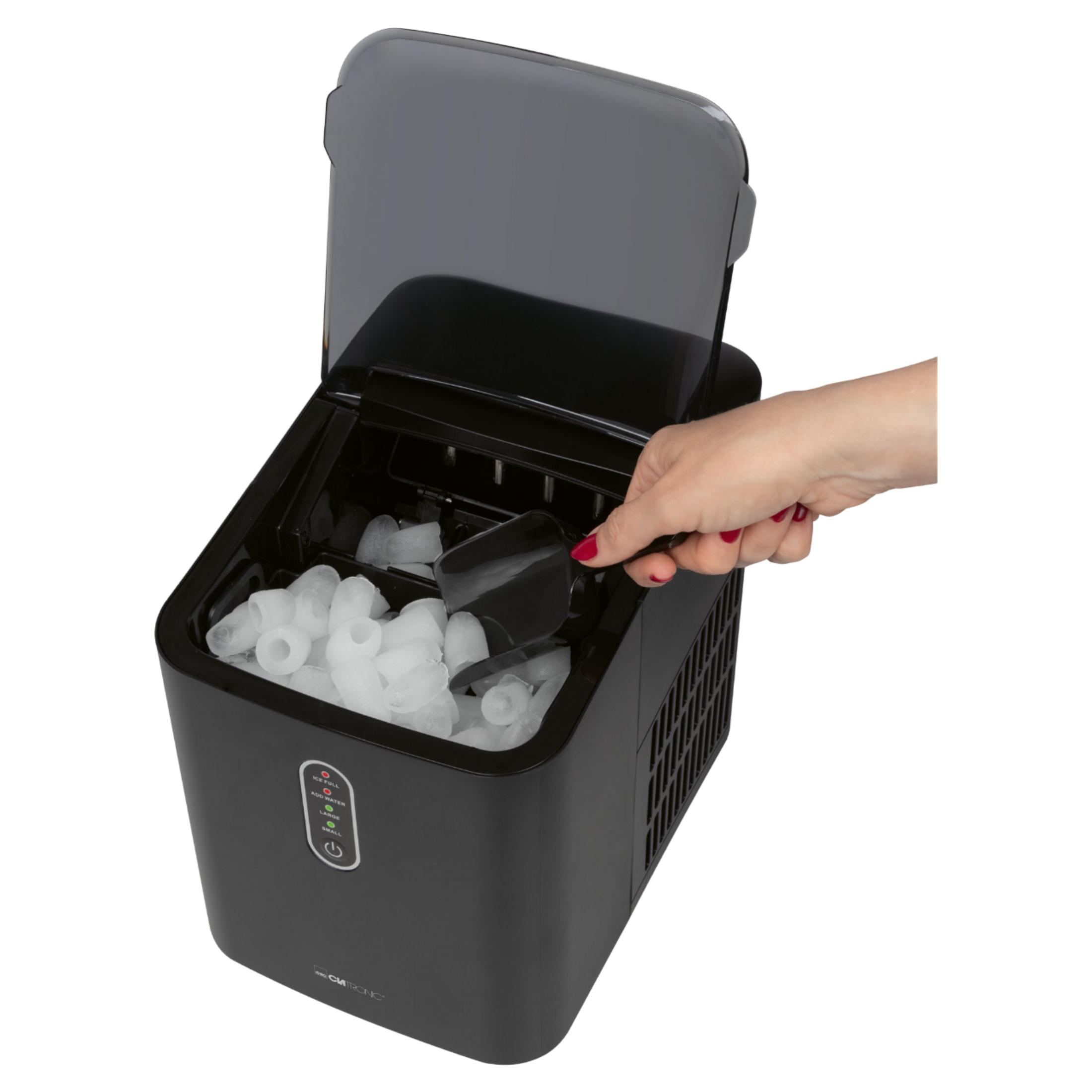 Eine Hand nimmt mit einer Schaufel Eiswürfel aus einer offenen schwarzen Eismaschine vor weißem Hintergrund.