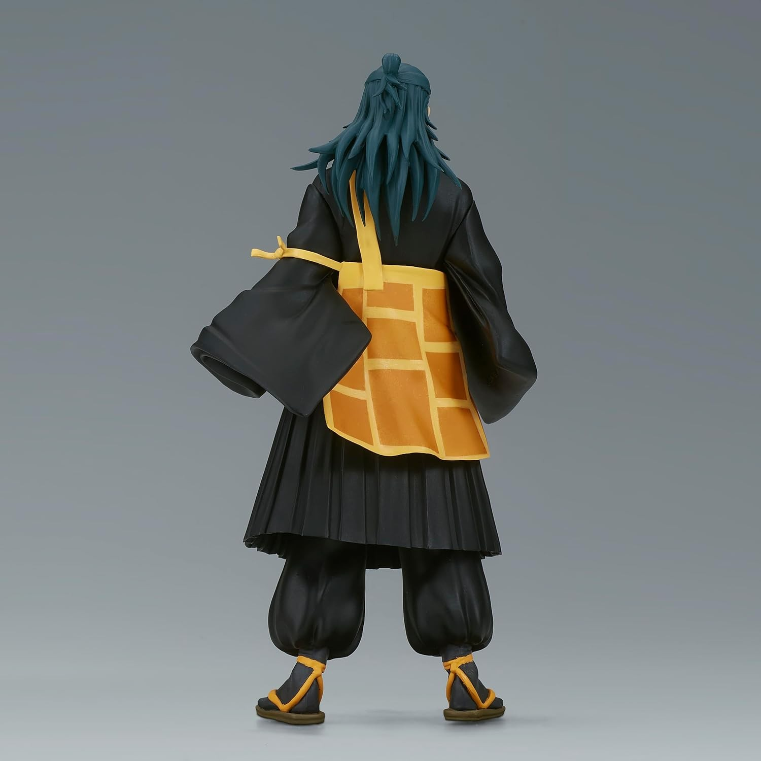 Vista trasera de una figura de anime con pelo azul largo, túnica negra, faja amarilla y sandalias sobre fondo gris.
