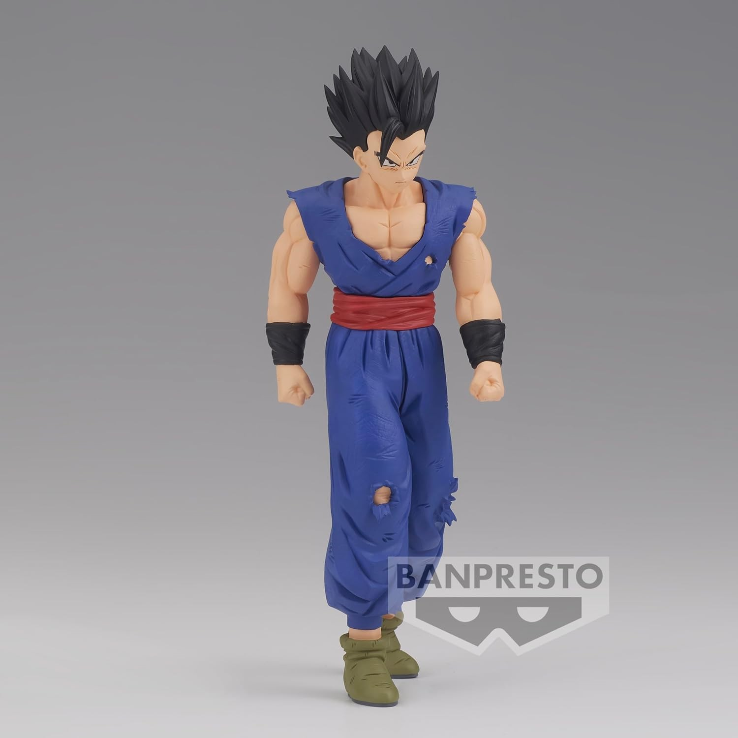 Eine detailgetreue Actionfigur von Gohan in blauer Uniform mit rotem Gürtel vor grauem Hintergrund.