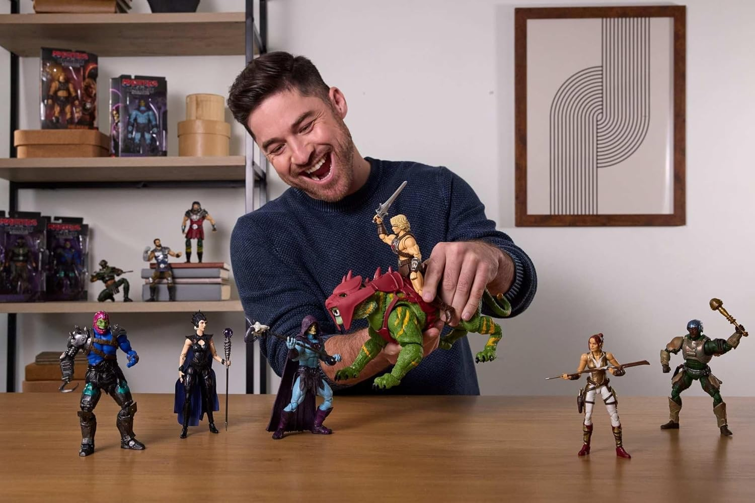 Un hombre feliz juega con figuras de acción en una mesa, incluyendo una bestia verde y héroes.