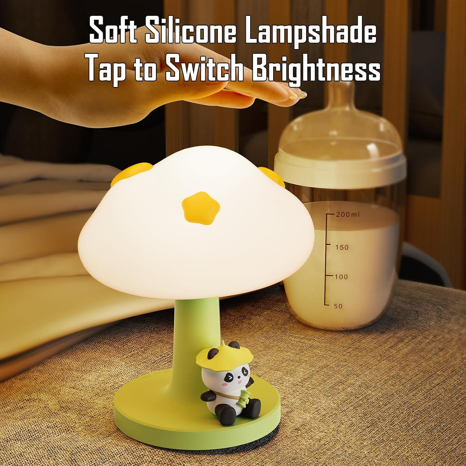Eine Hand tippt auf eine weiche Silikon-Pilzlampe mit einer süßen Pandabigur am grünen Stiel neben einer Babyflasche.