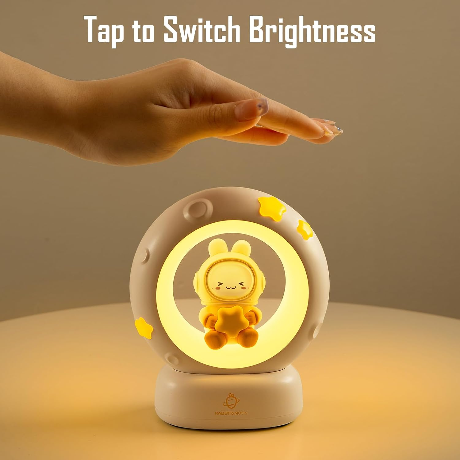 Eine Hand tippt auf eine runde Mondlampe mit einem gelben Hasen und Sternen.
