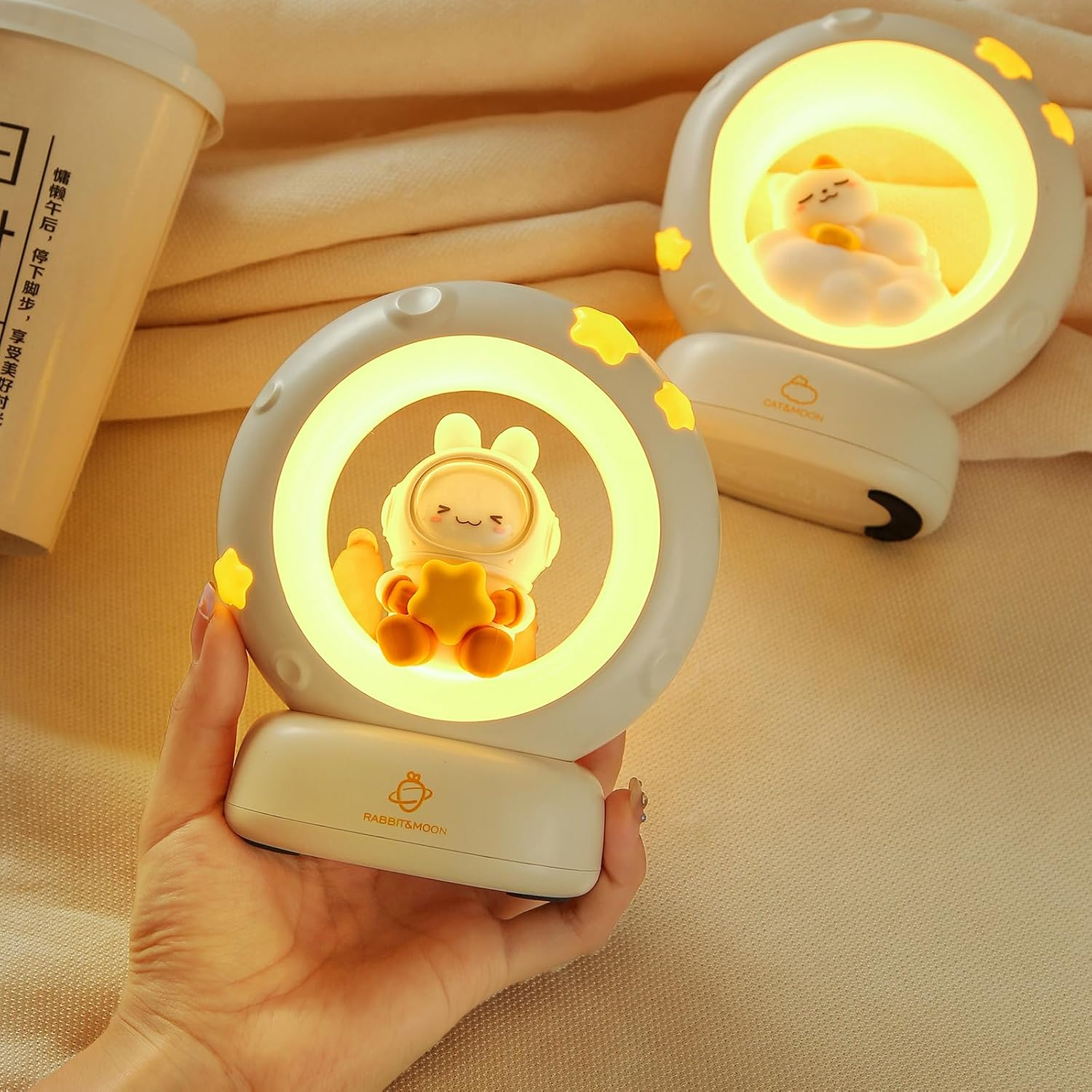 Eine Hand hält eine runde Nachtlampe mit einem kleinen Astronauten in der leuchtenden Mitte.