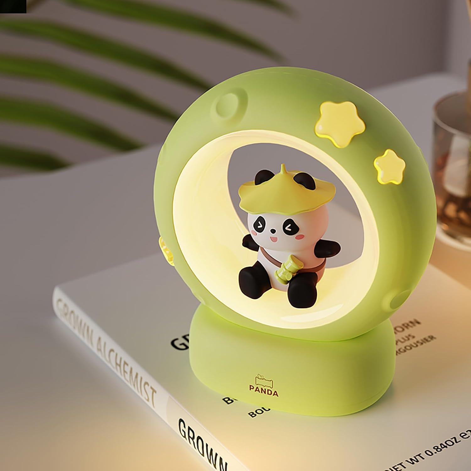 Eine grüne kreisförmige Panda-Nachtlampe steht auf einem Buch.