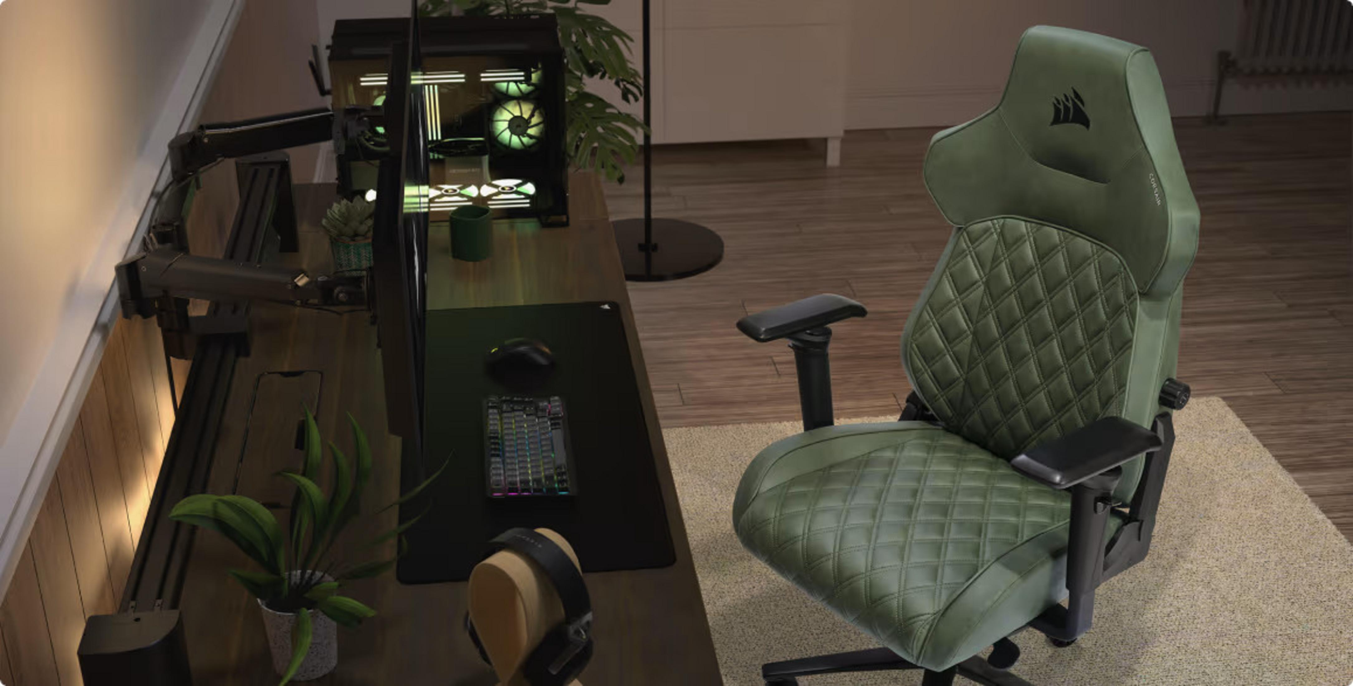 Ein grüner Gaming-Stuhl steht an einem Schreibtisch mit PC, Tastatur und Monitor in einem Zimmer mit Holzfussboden.