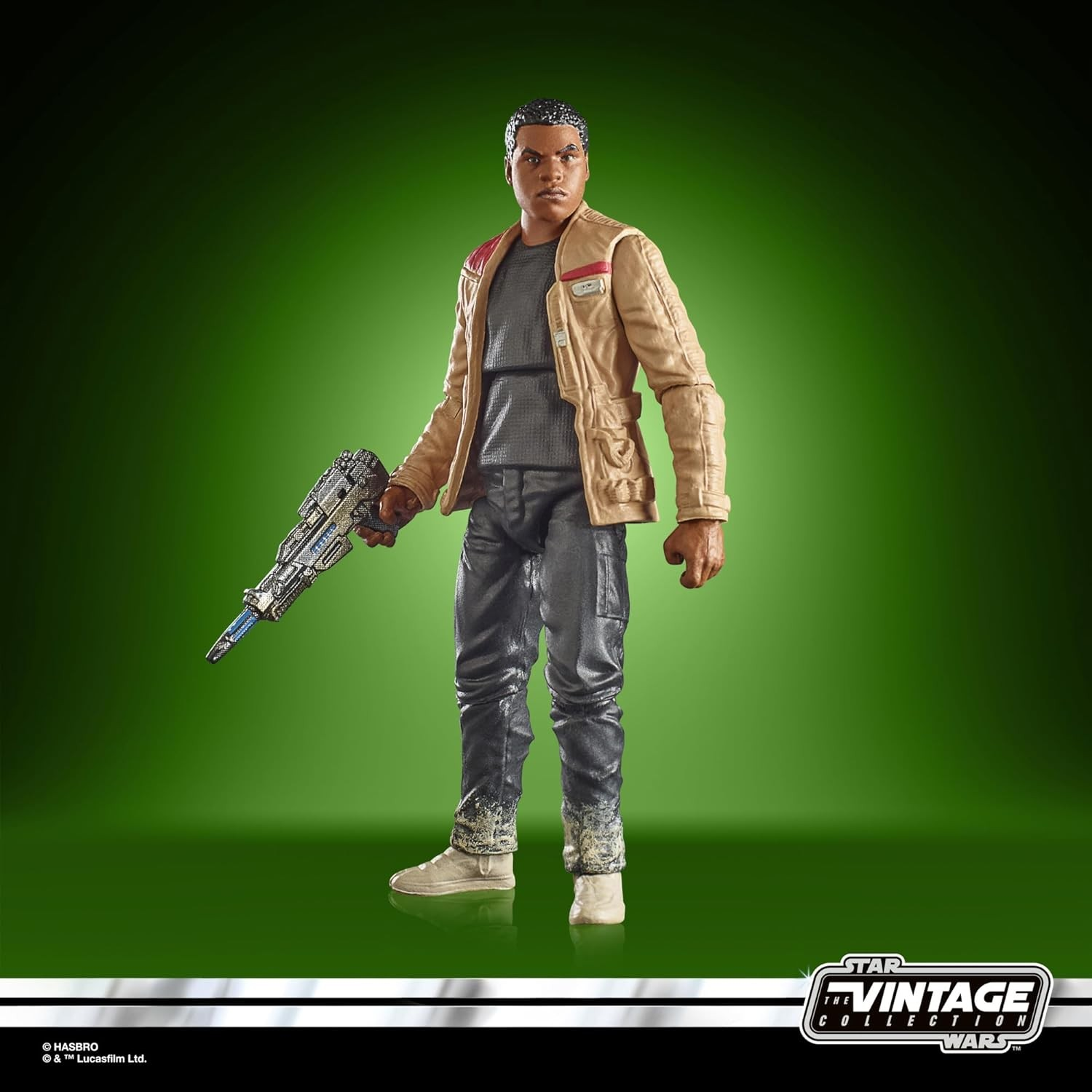 Figura de acción de Finn de Star Wars con chaqueta beige y ropa oscura, sosteniendo un bláster, sobre fondo verde.