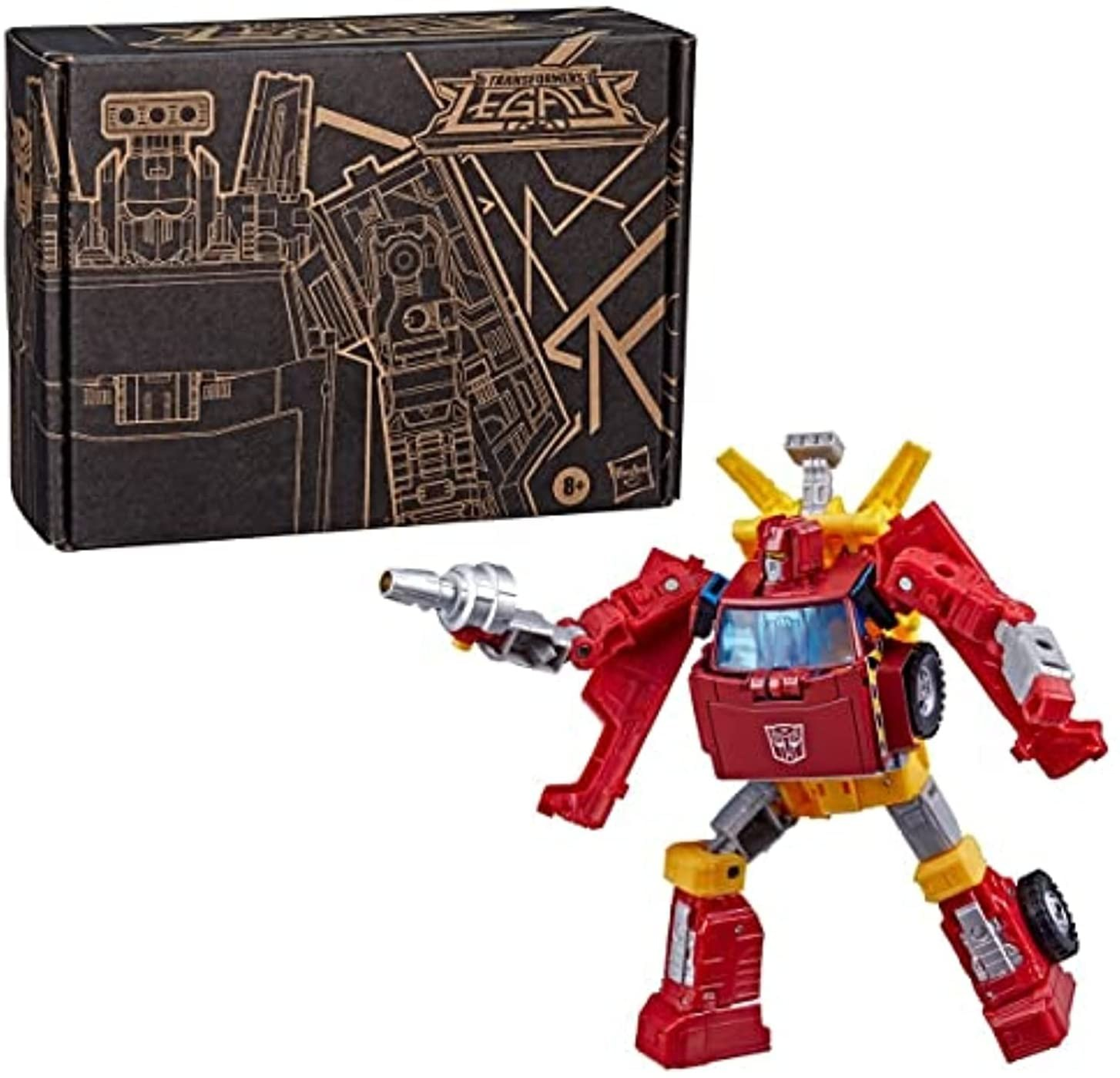Figura de acción Transformers Legacy en rojo y amarillo con arma frente a su caja negra.