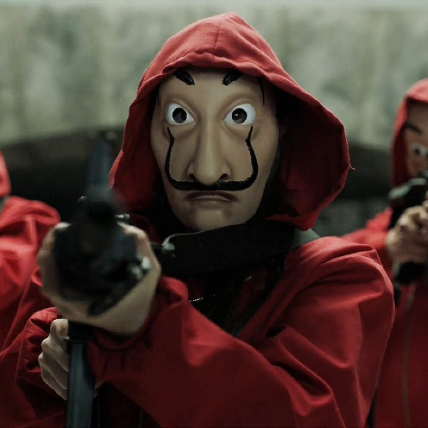 Persona con mono rojo con capucha y máscara de Dalí sosteniendo un arma.