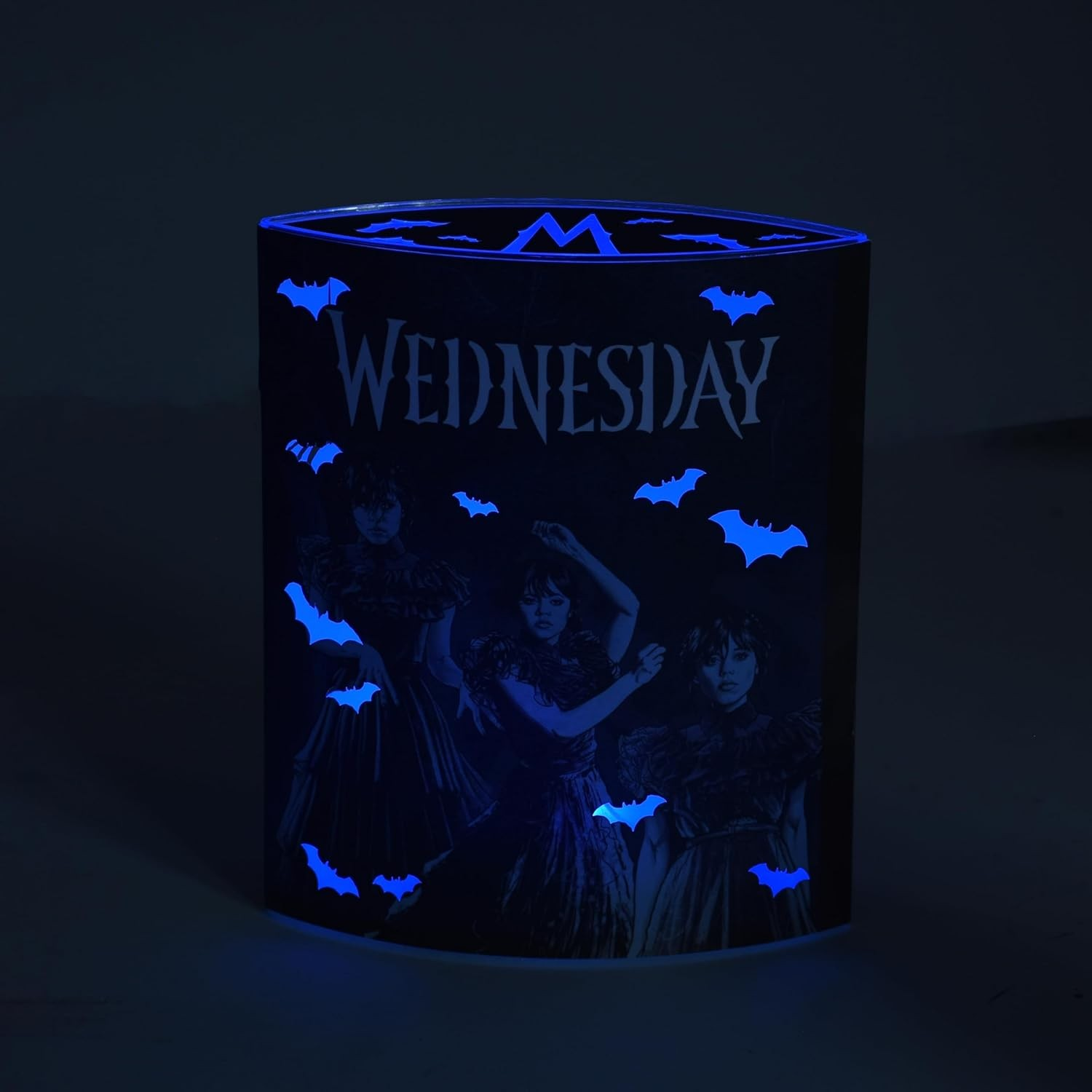 A dark blue glowing lamp featuring the word 'Wednesday' and small bats on a black background.