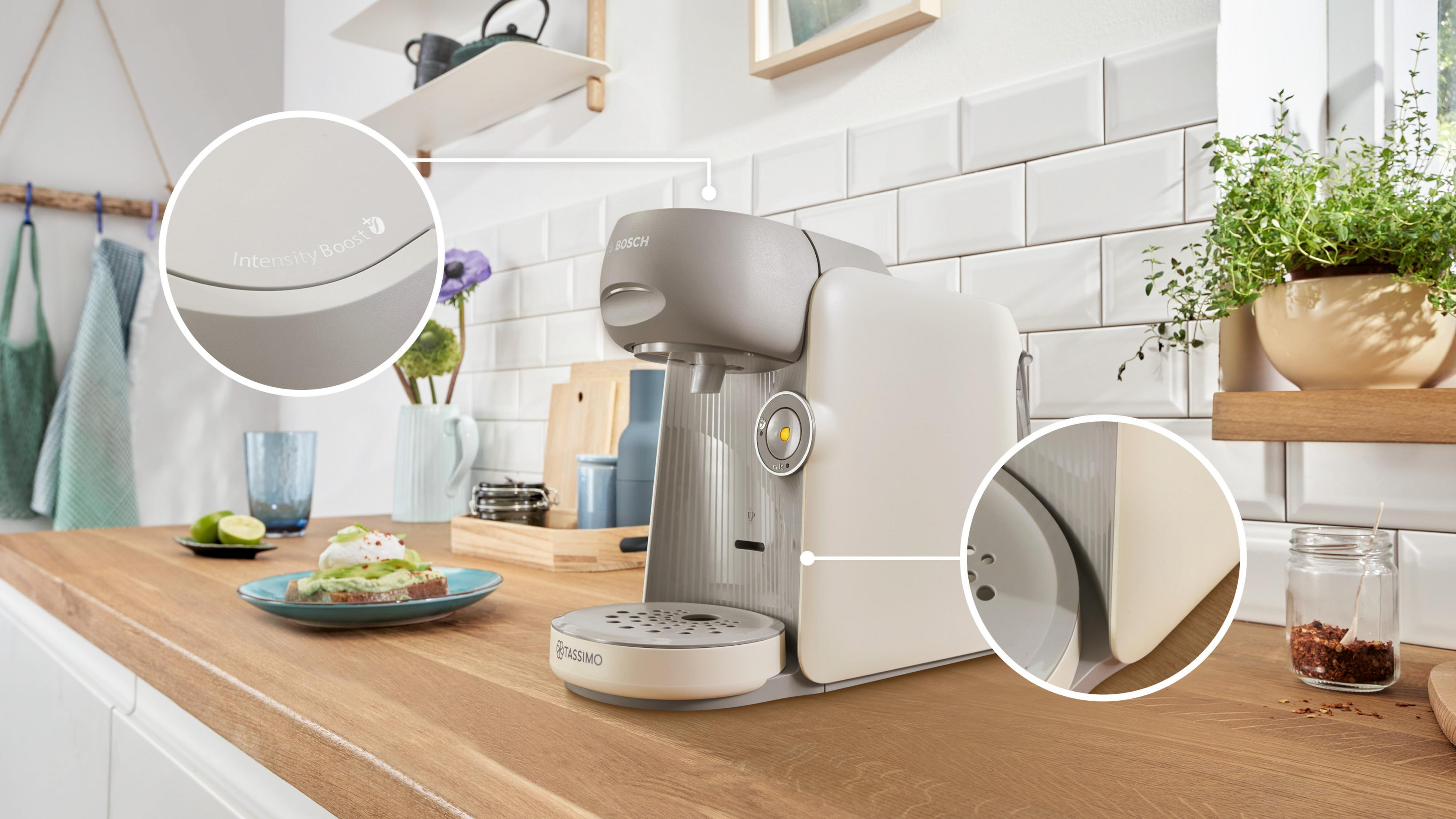 Macchina da caffè Bosch Tassimo beige e grigia su piano in legno in cucina con due cerchi di zoom.