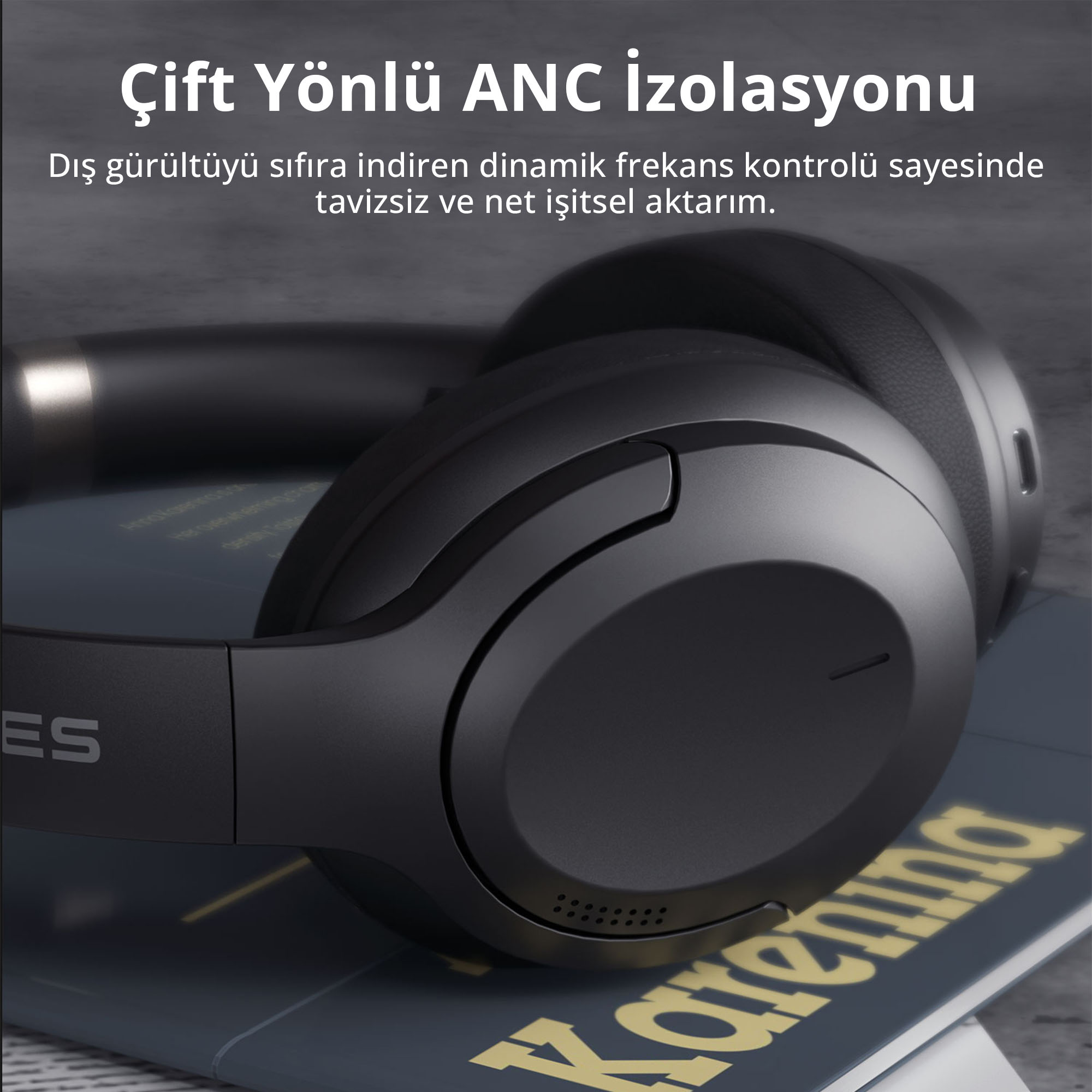 Bir kitap üzerinde duran ANC izolasyonlu siyah kulak üstü kulaklık.