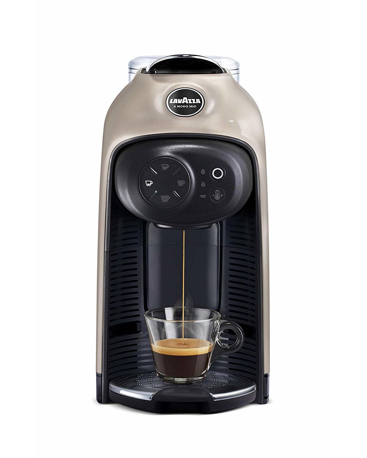 Cafetera Lavazza beige preparando espresso fresco en una taza de vidrio sobre la bandeja de goteo negra.
