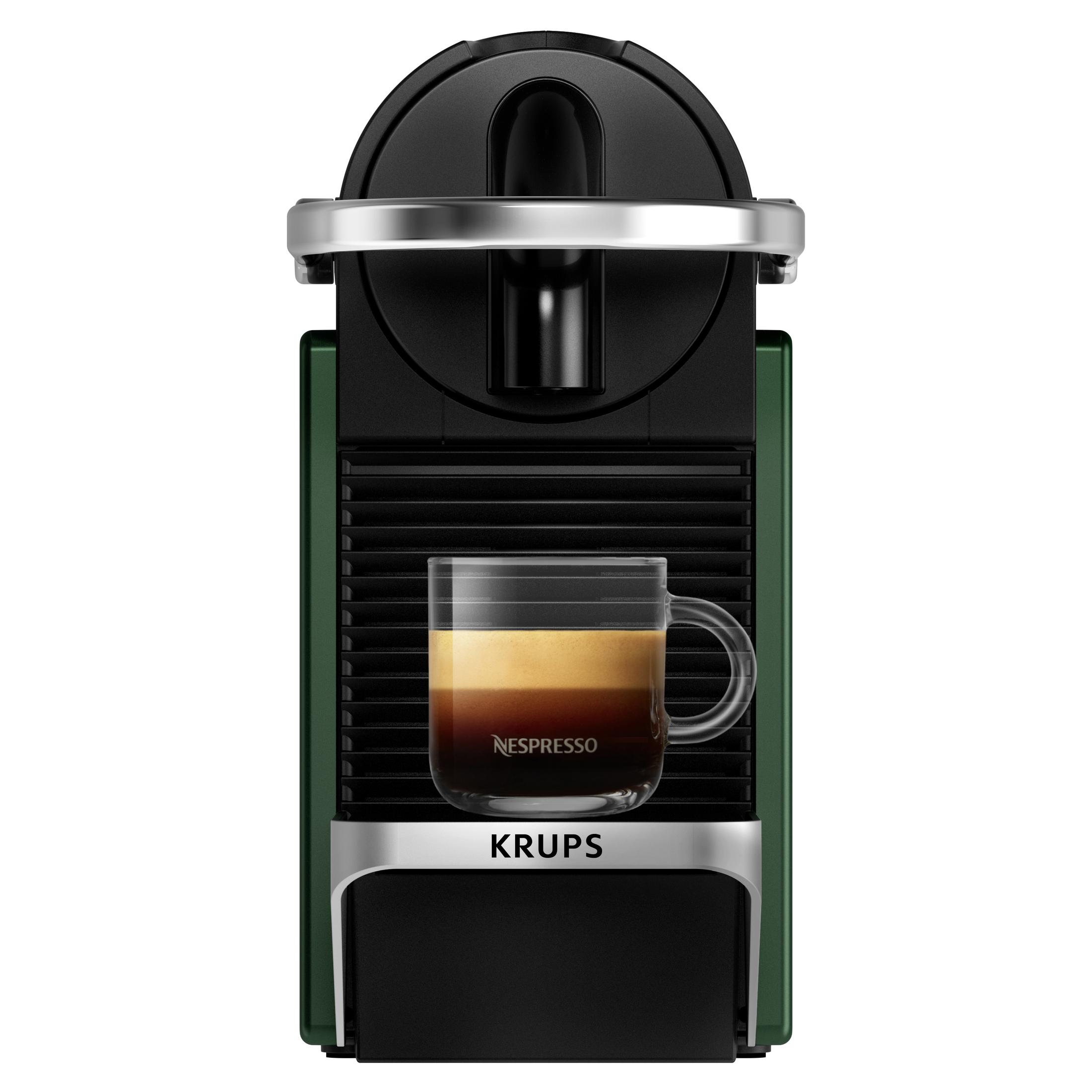 Una cafetera Krups verde y negra con una taza de vidrio llena de café en la bandeja.