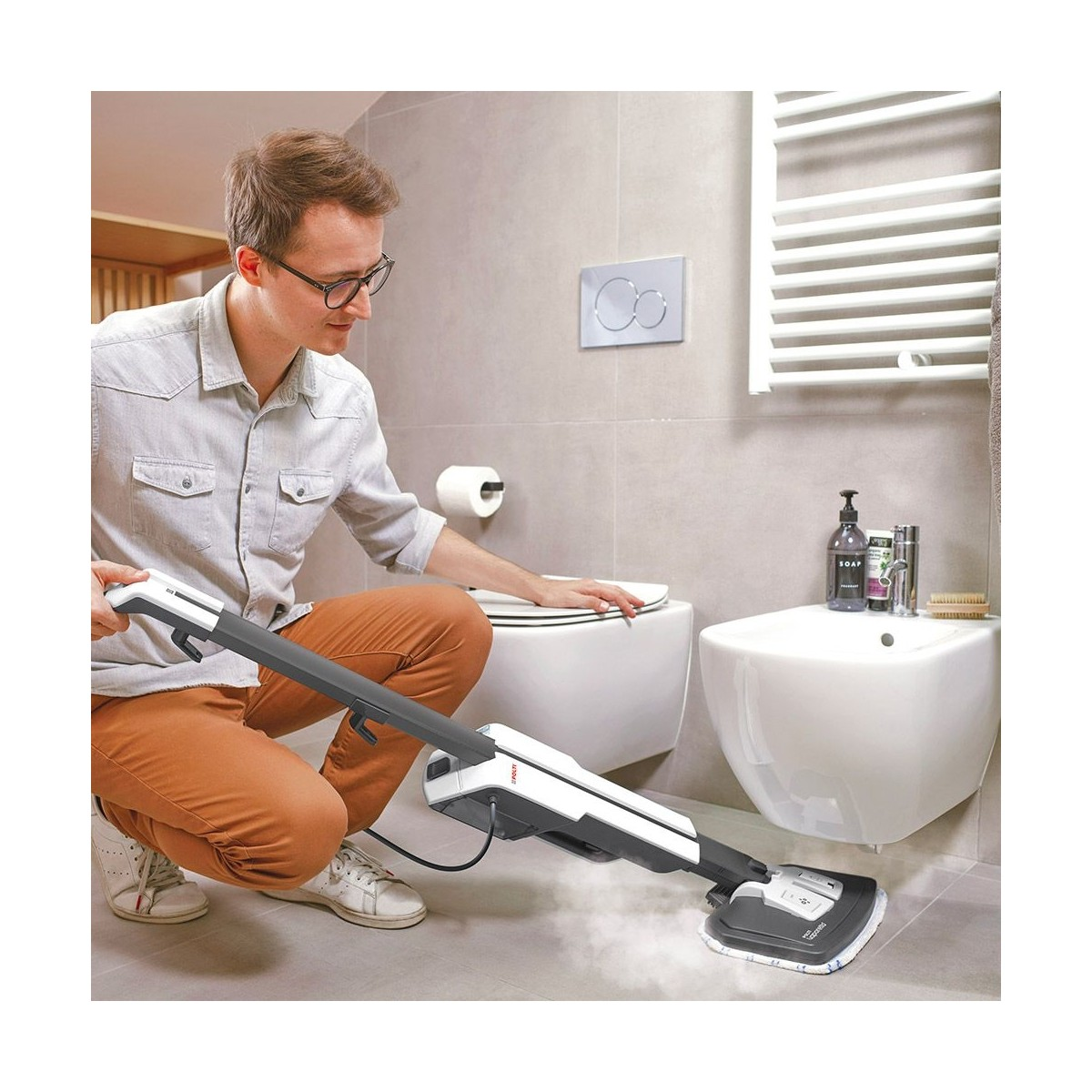 Ein Mann kniet in einem modernen Badezimmer und reinigt den Boden mit einem Dampfwischer.