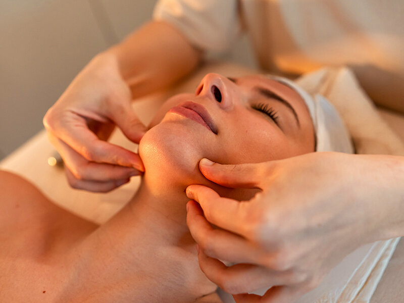 Una mujer recibe un suave masaje facial en un spa.