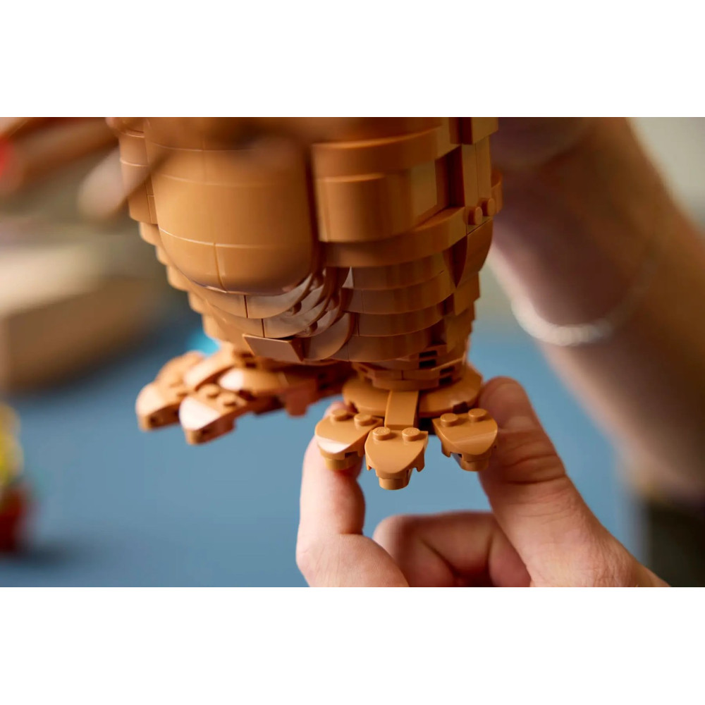 Ręce trzymają zbudowaną brązową figurkę Lego z pazurami.