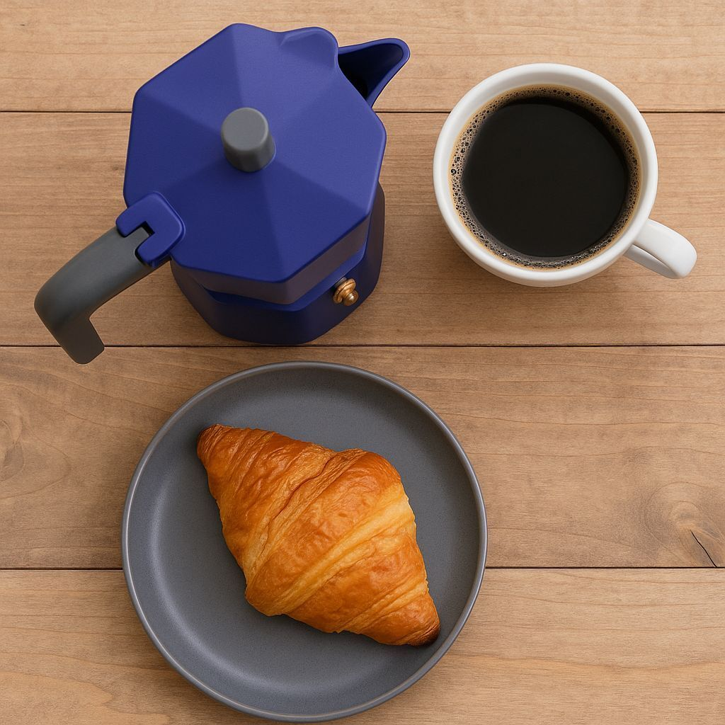 Caffettiera moka blu, tazza di caffè bianca e croissant su piatto grigio su legno.