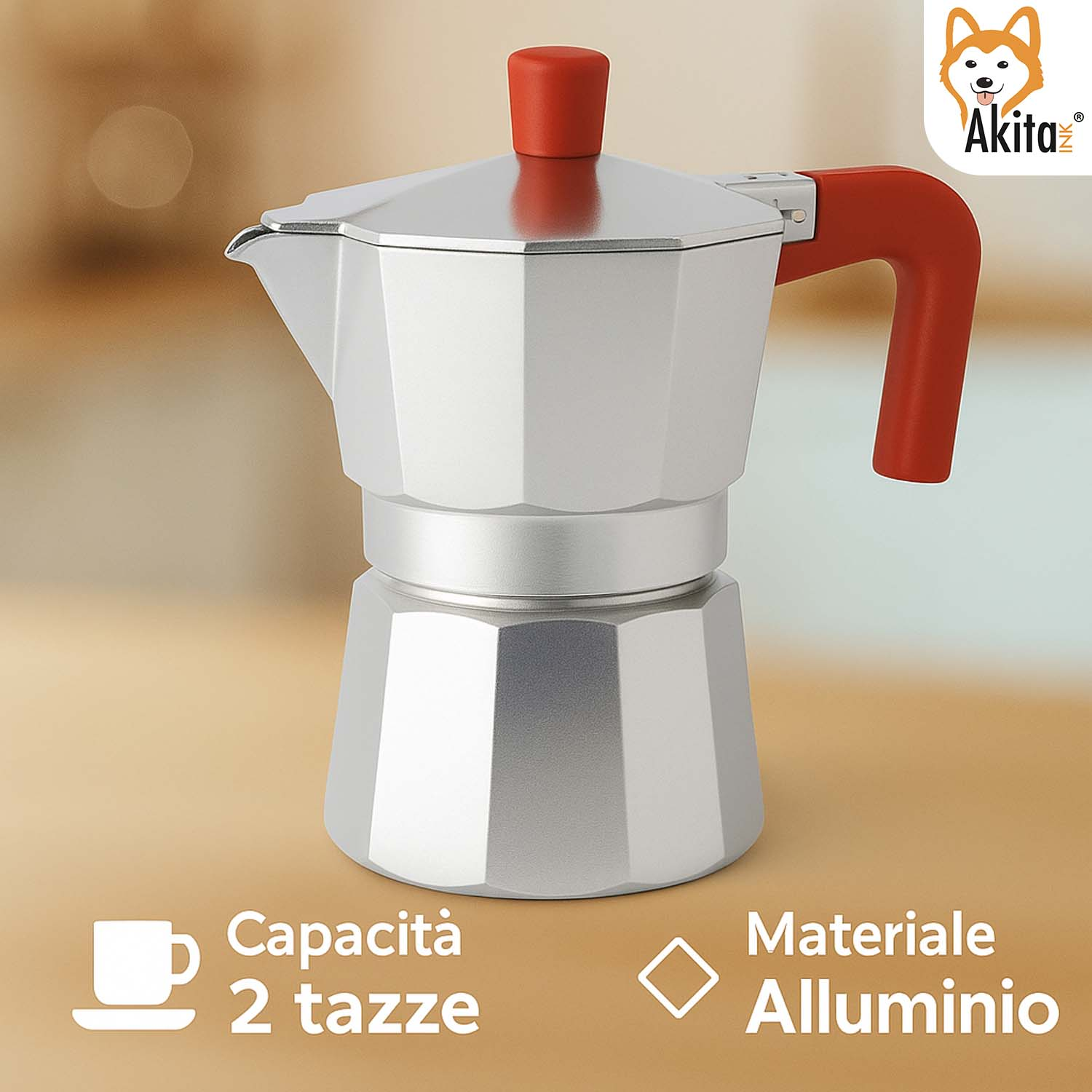 Una moka in alluminio argentato con manico e pomello rossi su superficie beige.