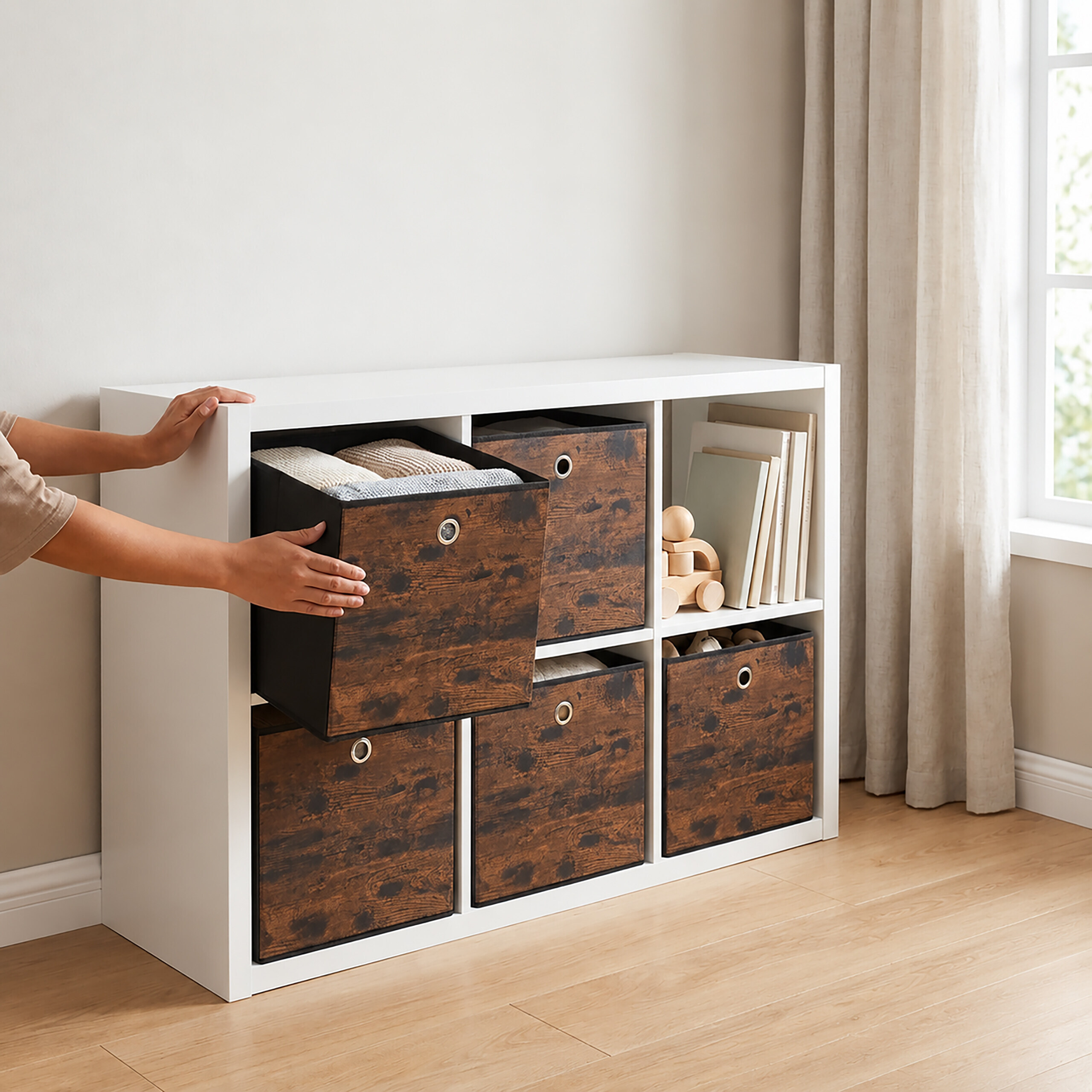 Eine Person zieht eine holzfarbene Stoffbox aus einem weißen Regal, das im Raum steht.