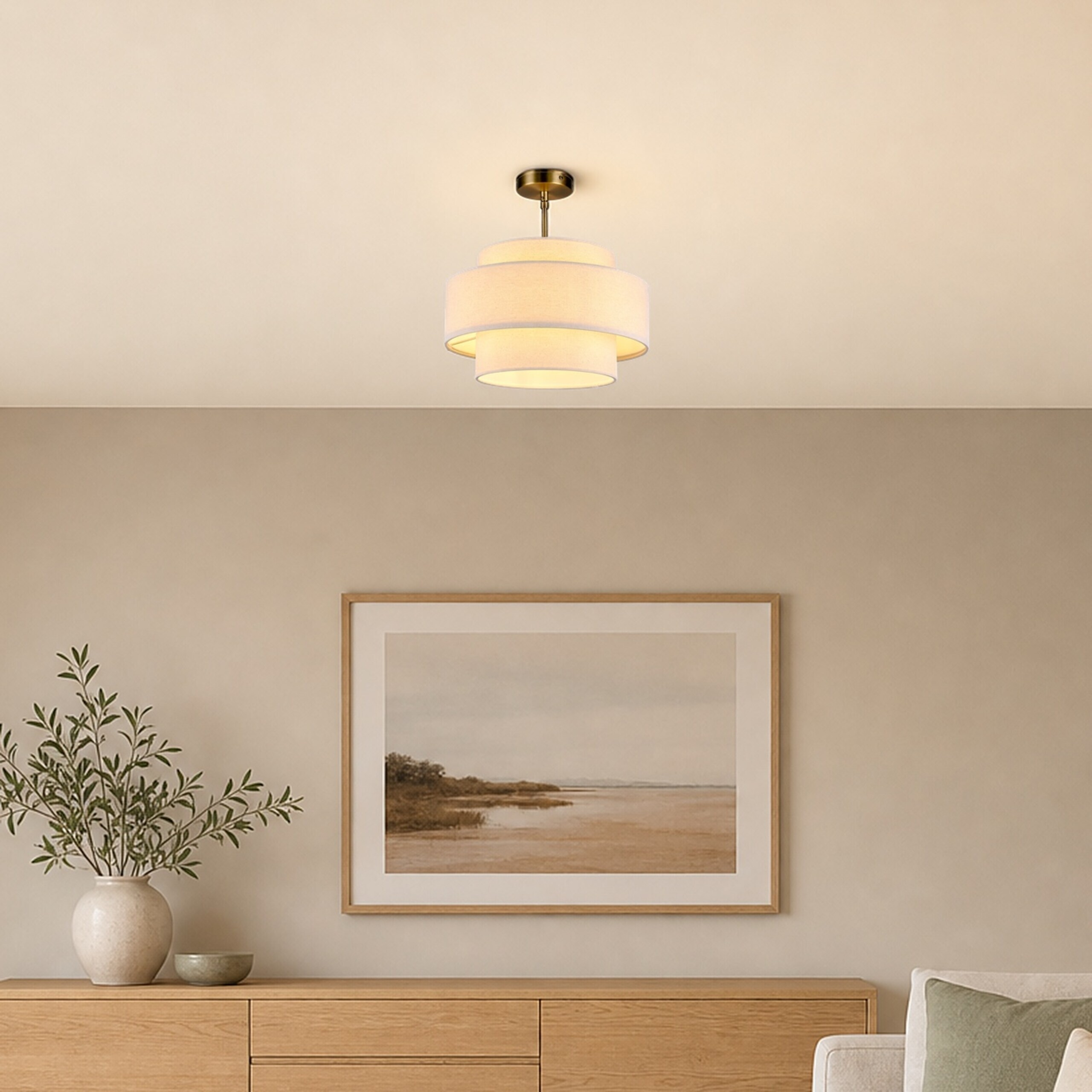 Eine dreistufige Stoffdeckenlampe beleuchtet einen Raum mit einer Holzkommode, einem Landschaftsbild und einer Vase.