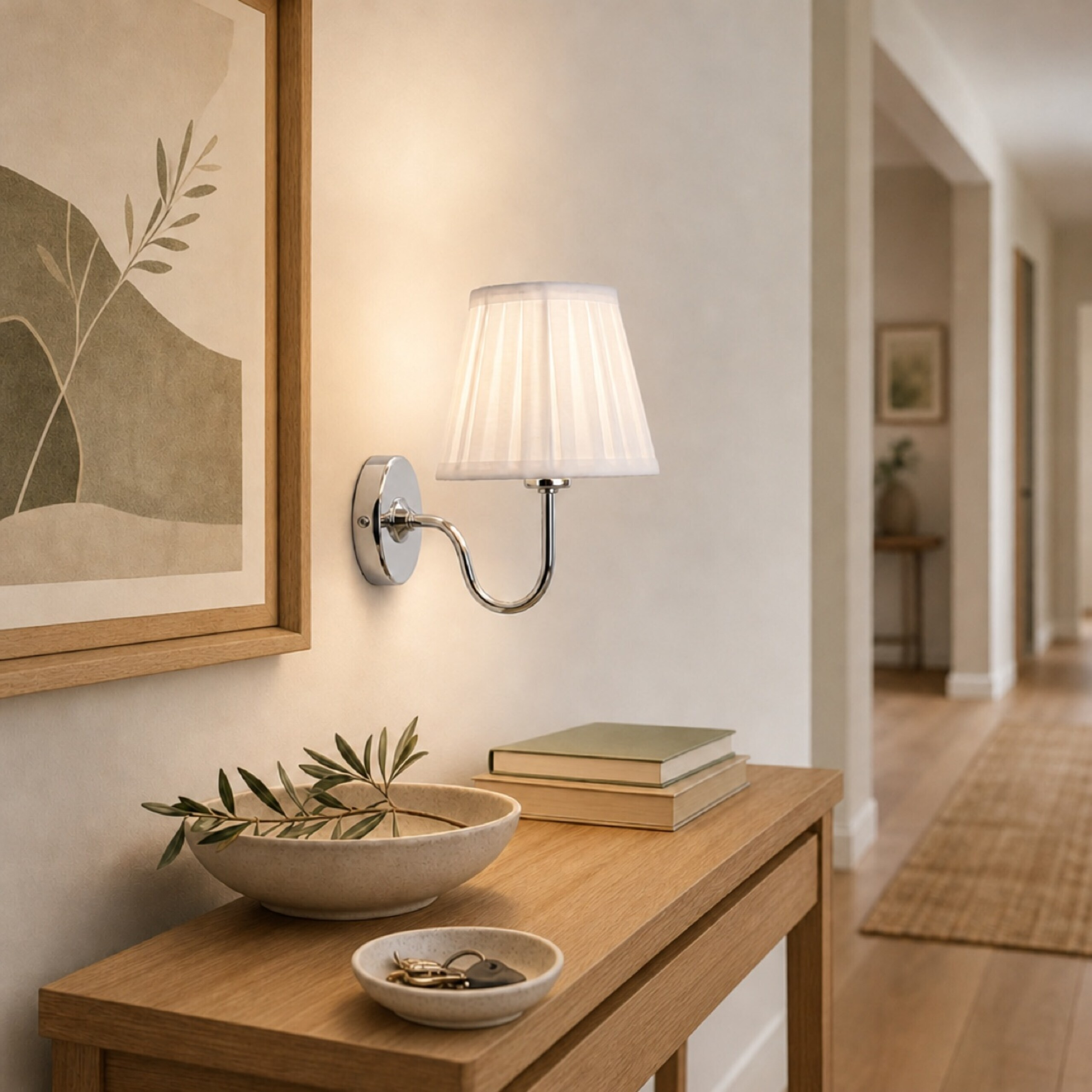 Eine weiße Wandlampe mit plissiertem Schirm hängt über einem Holztisch mit Deko in einem Flur.
