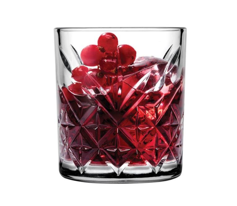 Beyaz arkaplanda kirmizi icecek, buz ve kirmizi meyveler iceren kristal bardak.