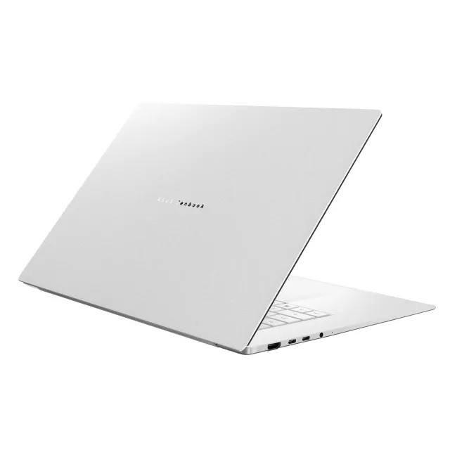 Srebrny laptop Asus Zenbook ustawiony pod kątem na białym tle, pokazujący smukłą klapę i porty.