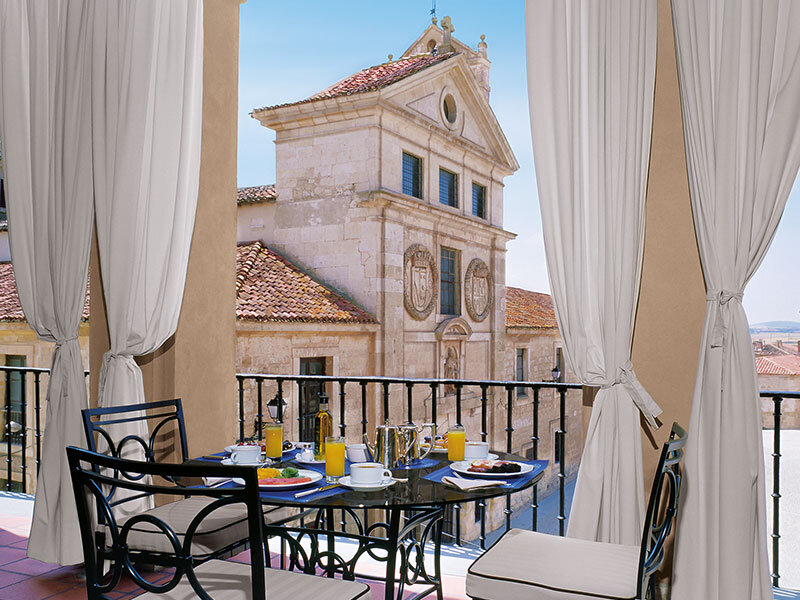 Mesa de desayuno en un balcón con vistas a un edificio histórico.