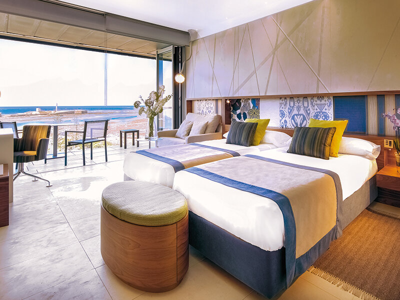 Habitación de hotel moderna con dos camas y vista al mar.