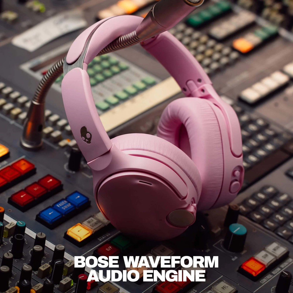 Auriculares rosados cuelgan en una mesa de mezclas con botones coloridos.