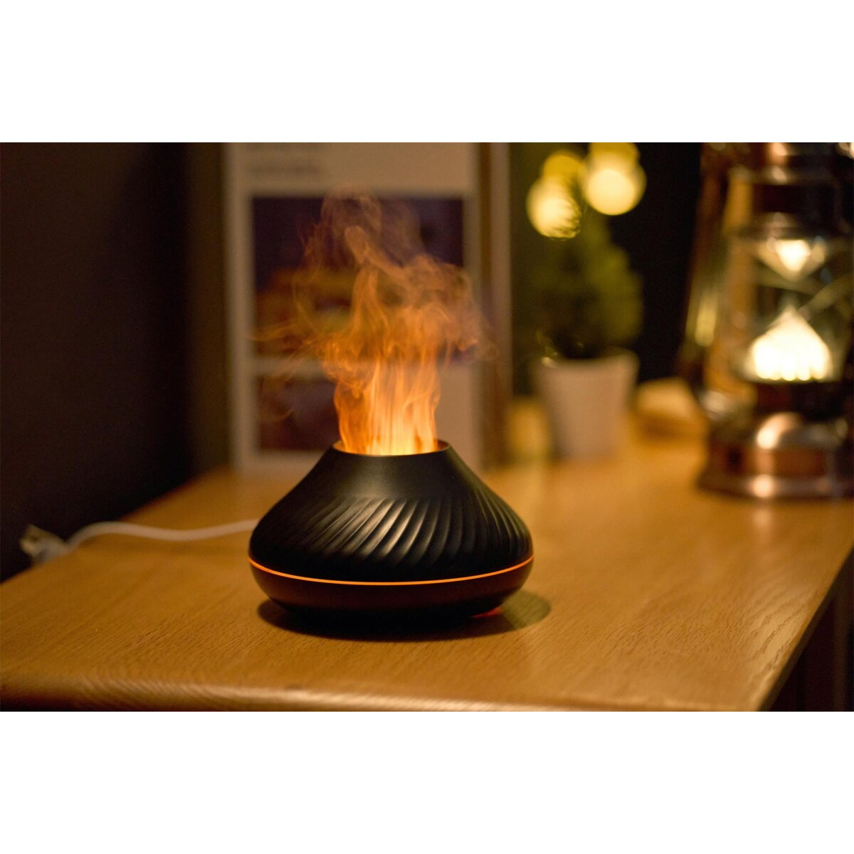 Ein schwarzer Flammeneffekt-Diffusor auf einem Holztisch, der orange beleuchteten Nebel ausstößt.