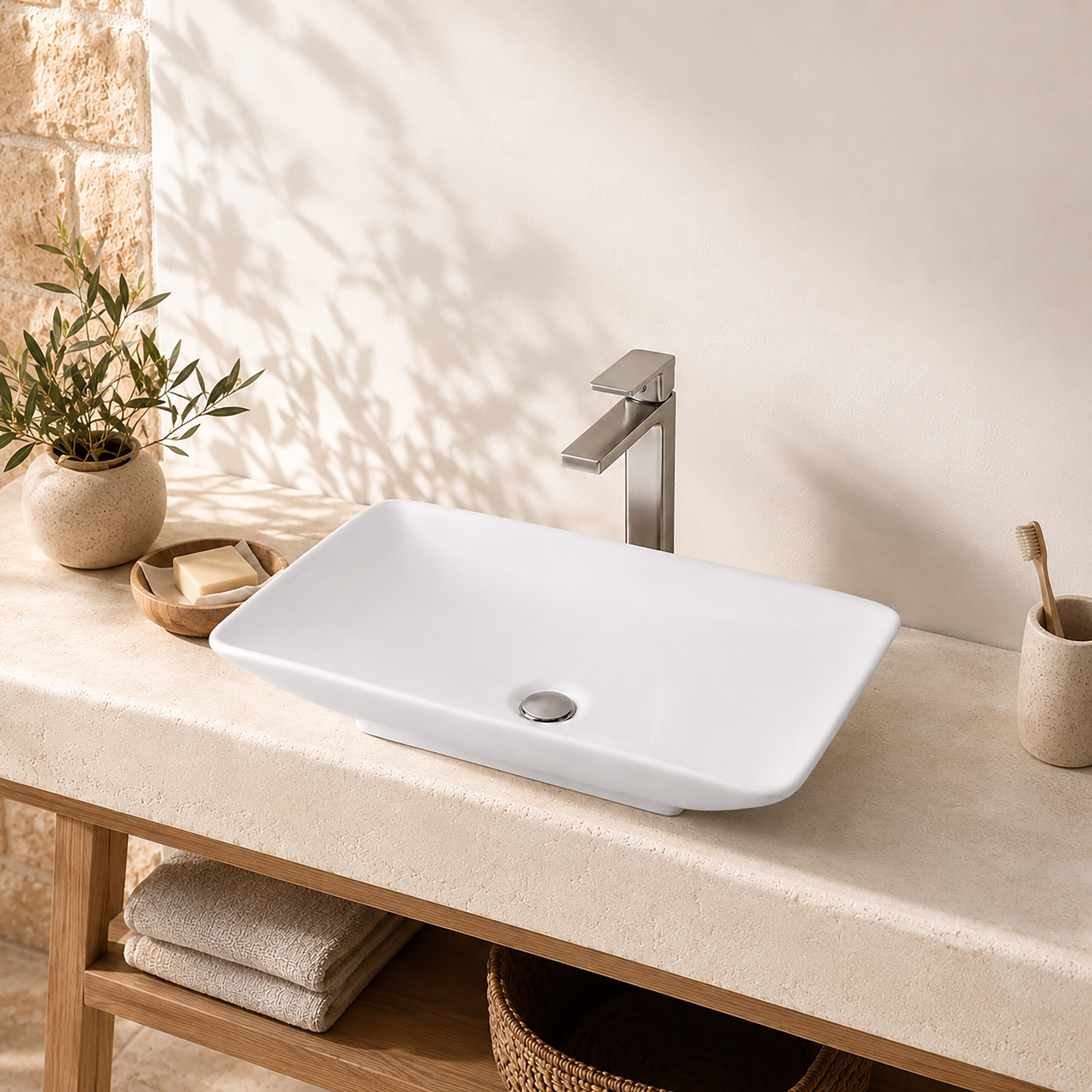 Ein weißes Waschbecken auf einer Steinplatte mit modernem Wasserhahn, Pflanze, Seife und gefalteten Handtüchern.
