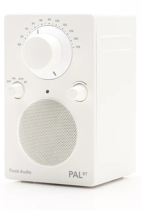 Weißes Tivoli Audio PAL BT Radio mit großem Drehregler, kleinerem Schalter und Lautsprechergitter auf weißem Grund.