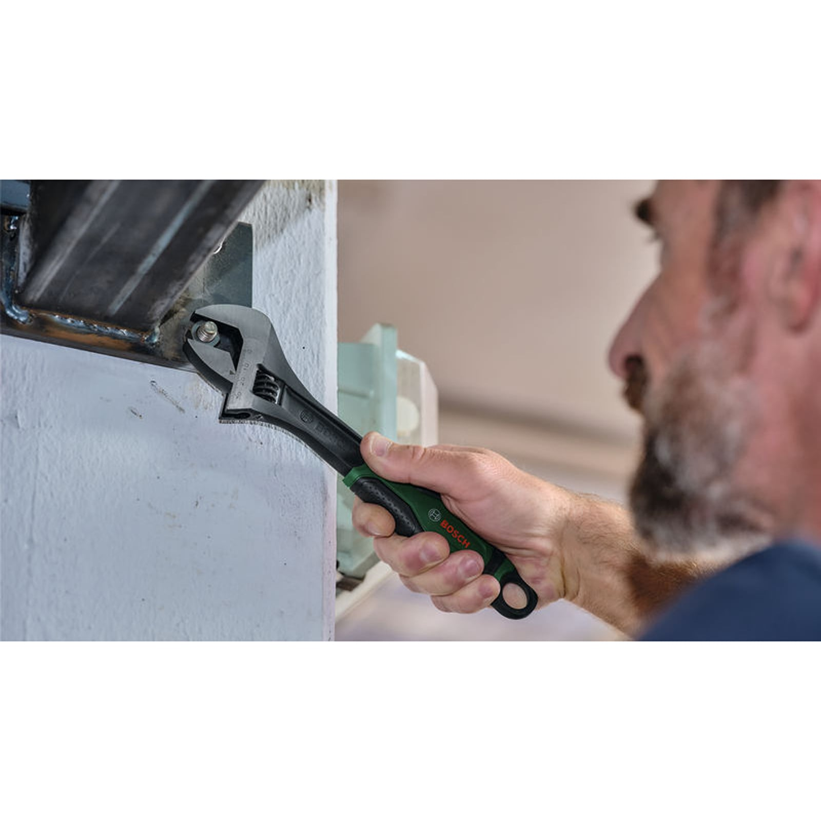 Ein Mann nutzt einen verstellbaren Bosch-Schraubenschlüssel an einer Metallmutter.