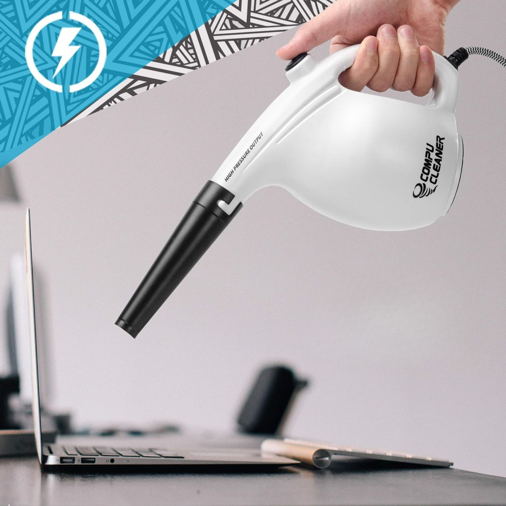 Eine Hand hält einen weißen Compu Cleaner, der auf eine Laptop-Tastatur auf einem Schreibtisch gerichtet ist.