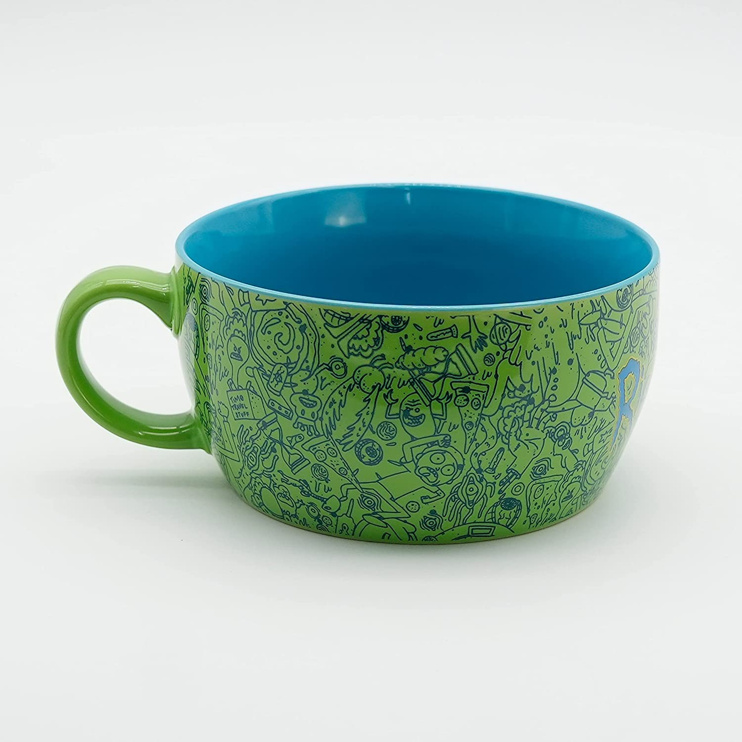 Bol verde con asa, interior azul y dibujos animados azules sobre fondo blanco.