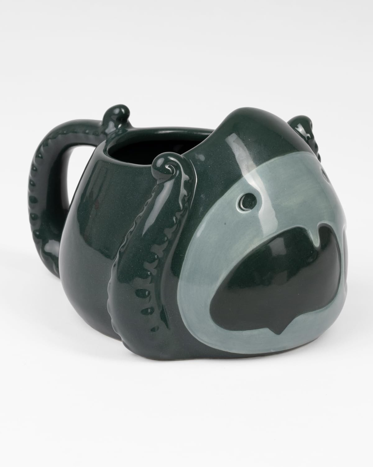 Taza de cerámica verde oscura con diseño de pulpo, asa de tentáculo y una boca abierta estilizada sobre fondo blanco.