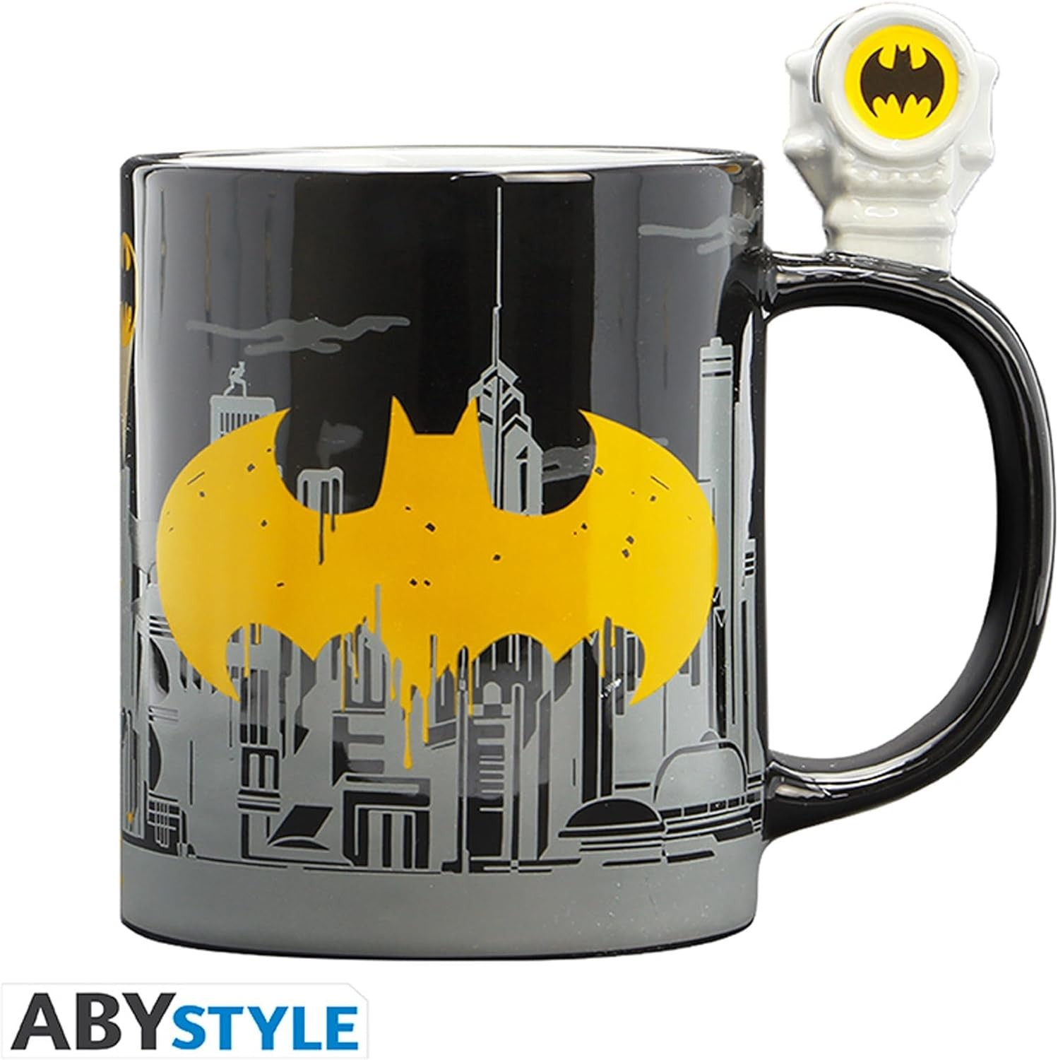 Una taza negra de Batman con logo amarillo, silueta de ciudad y asa con Bat-Señal.