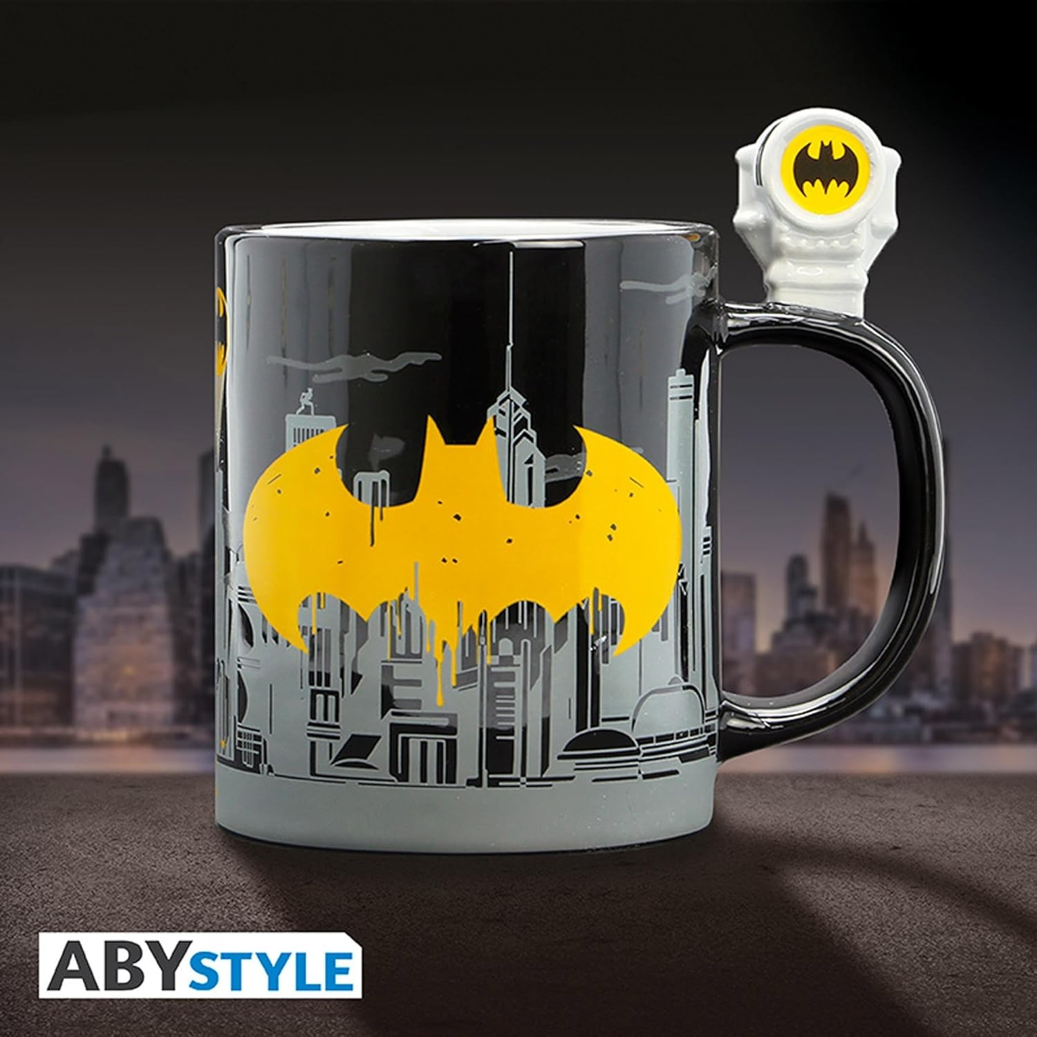 Taza negra de Batman con símbolo amarillo, diseño de Gotham City y figura de bat-señal en el asa.